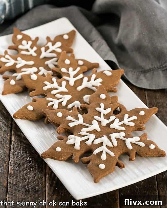 Three perfectly baked gingerbread snowflakes arranged on a pristine white platter, showcasing their intricate details and festive charm.