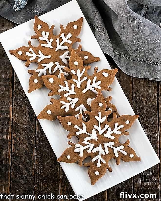 An overhead shot capturing three beautifully baked gingerbread snowflakes, artfully arranged to highlight their delicate designs and golden-brown hue.