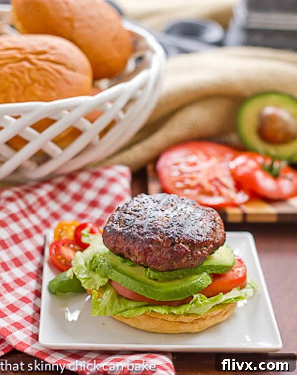 A delicious California Burger on a white plate, resting on a classic red and white checked napkin, highlighting its fresh ingredients.