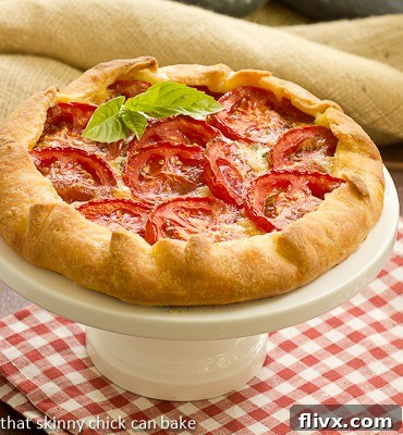 Close-up of Cheese and Tomato Galette ingredients being prepped on a wooden cutting board, including sliced tomatoes and fresh basil.
