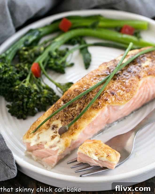 Roasted salmon on a plate with a fork taking a bite, highlighting the flaky and moist interior of the fish.