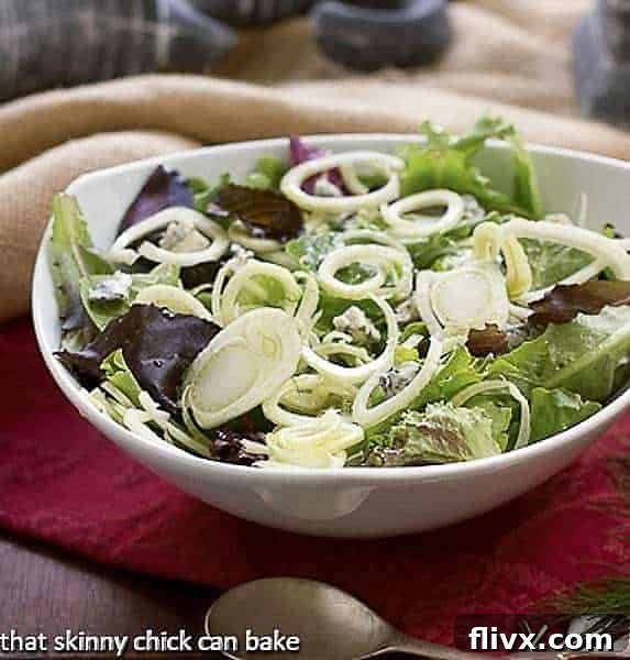 A vibrant Fennel and Gorgonzola Salad in a white serving bowl, showcasing thinly sliced fresh fennel, crumbled Gorgonzola, and a light dressing.