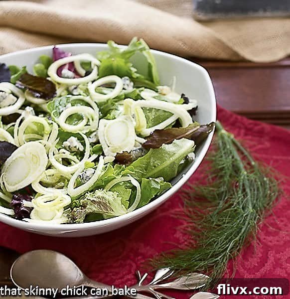 Fennel and Gorgonzola Salad presented beautifully in a white serving bowl, garnished with a fresh fennel frond, ready to be enjoyed.