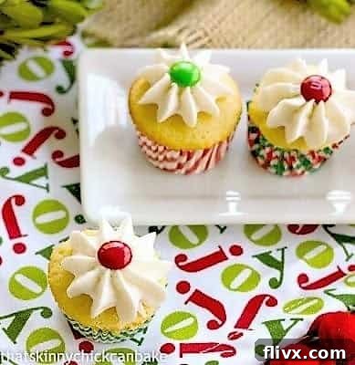 Three beautifully iced Holly Topped White Cupcakes adorned with M&M's and green candies, resting on a festive holiday napkin.
