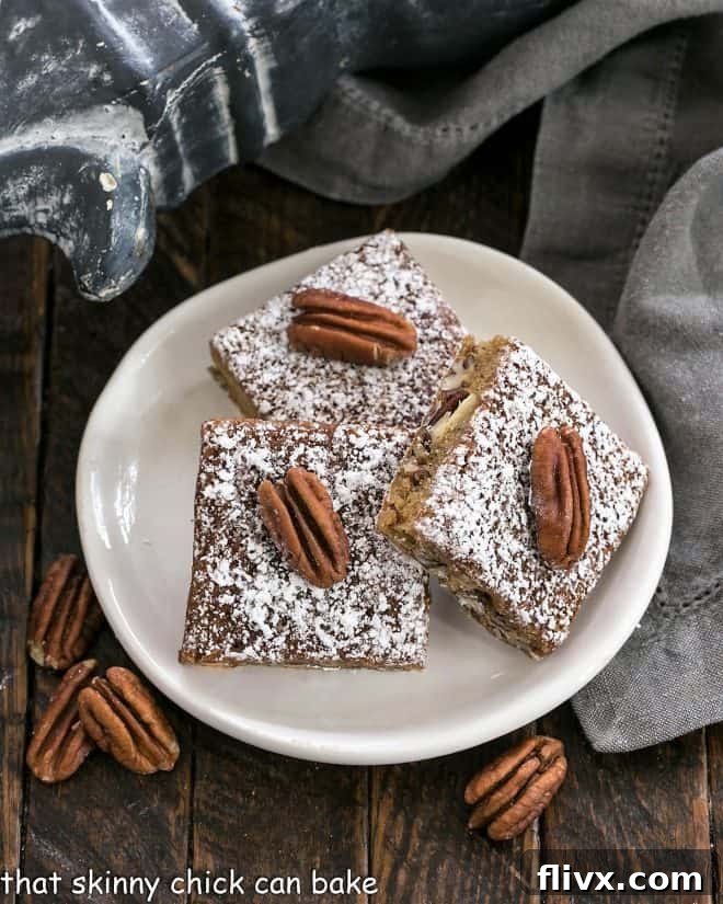 Three golden brown Southern Pecan Bars artfully arranged on a round white plate, showcasing their rich texture and pecan topping.