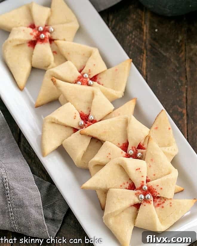 Overhead close-up view of a selection of festive pinwheel cookies, adorned with red sprinkles, artfully arranged on a clean white tray.