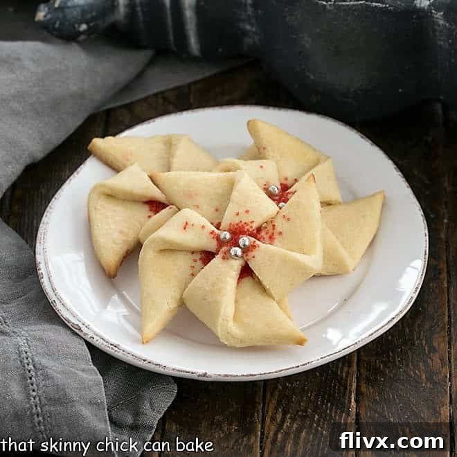 3 Poinsettia Cookies on a small white dessert plate, with vibrant red centers.