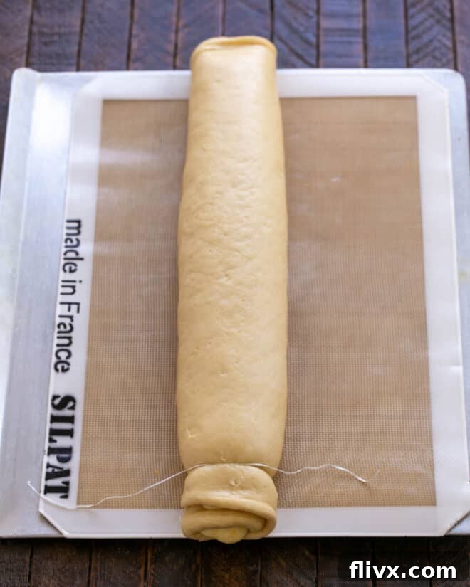 Fluffy Orange Glazed Rolls 14 Dough log being sliced into individual rolls using unflavored dental floss.