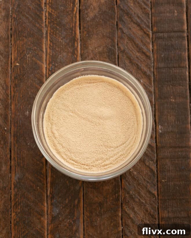 Fluffy Orange Glazed Rolls 4 Yeast and warm water in a small bowl, showing the beginning of yeast activation.