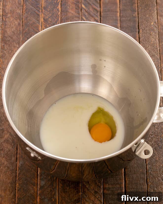 Fluffy Orange Glazed Rolls 6 Cooled scalded milk, room temperature butter, and an egg added to the mixer bowl.
