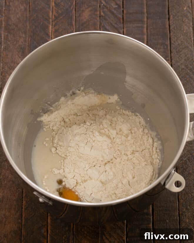 Fluffy Orange Glazed Rolls 7 Sugar, salt, and flour being added to the mixture in the stand mixer.