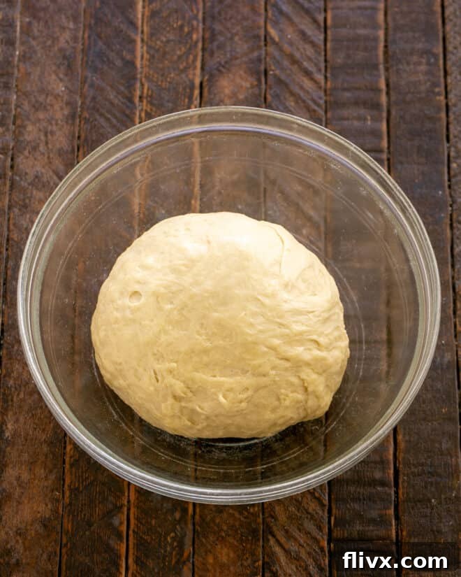 Fluffy Orange Glazed Rolls 8 Dough in a stand mixer with a paddle attachment, then kneaded with a dough hook, and finally placed in a greased bowl to proof.