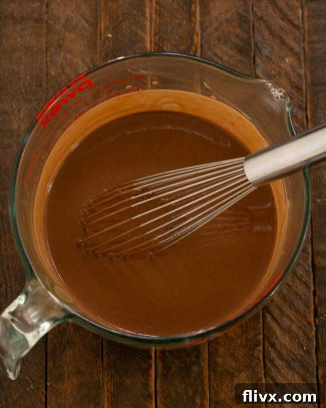 A bowl containing the finished chocolate pudding mixture being whisked vigorously until all ingredients are thoroughly combined and smooth.