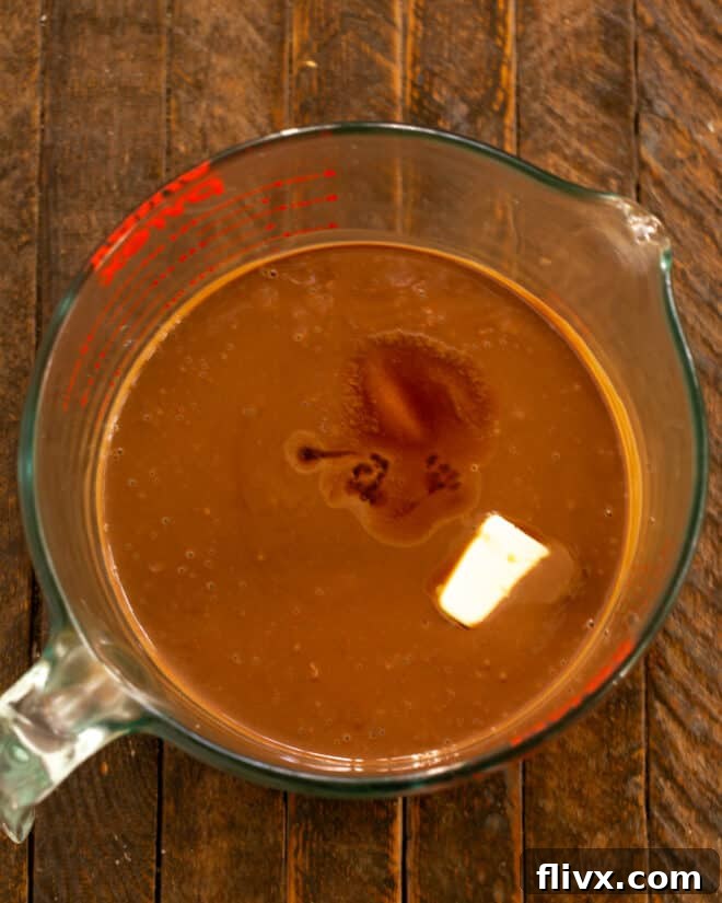 Butter, salt, and vanilla extract being added to the melted chocolate and custard mixture, enhancing its flavor.