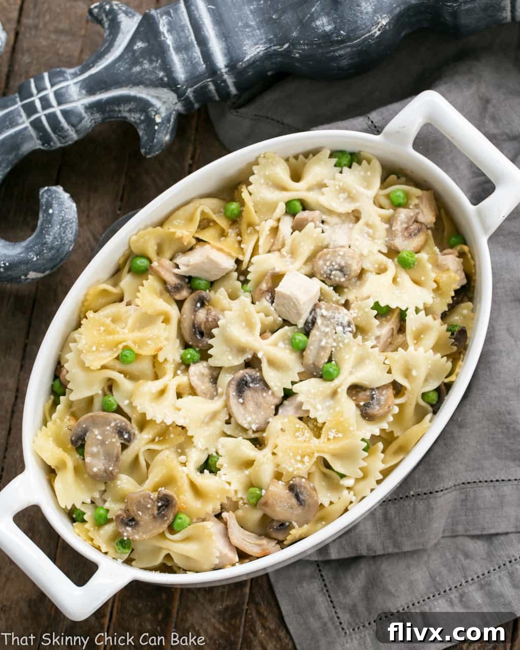 Overhead view of a golden-brown homemade Turkey Tetrazzini casserole in an oval white baking dish, perfect for Thanksgiving leftovers.