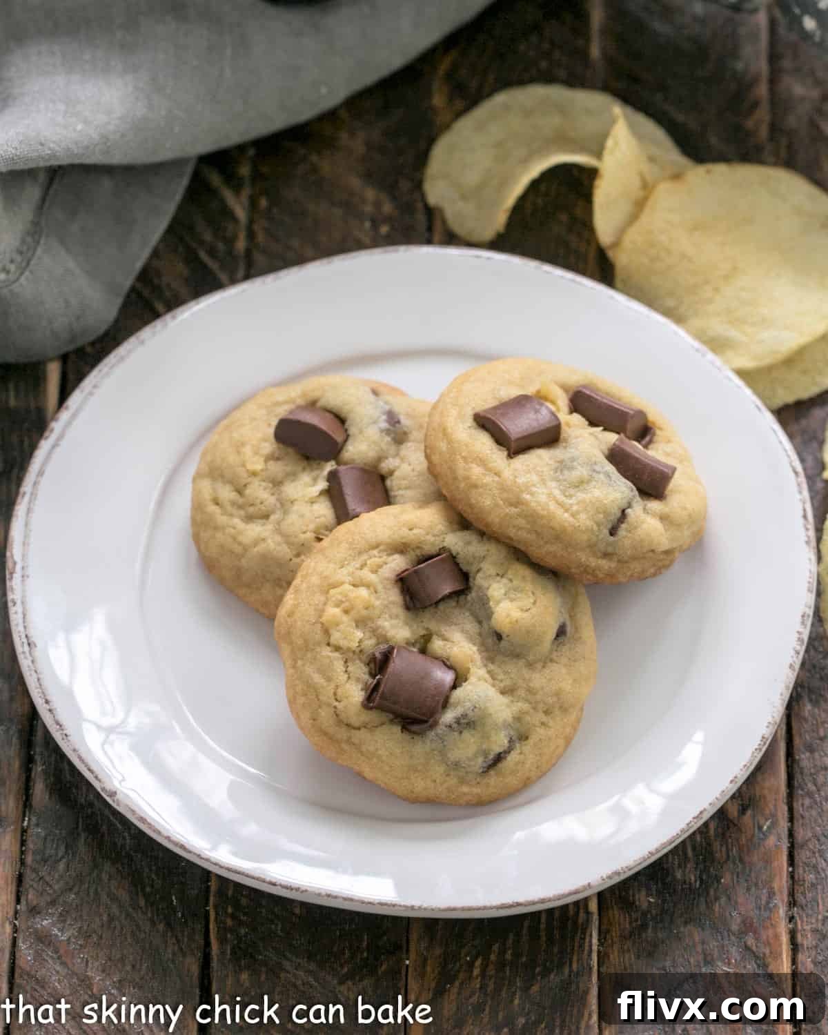 Overhead view of 3 potato chip cookies on a white dessert plate, showcasing their inviting texture and chocolate chunks.