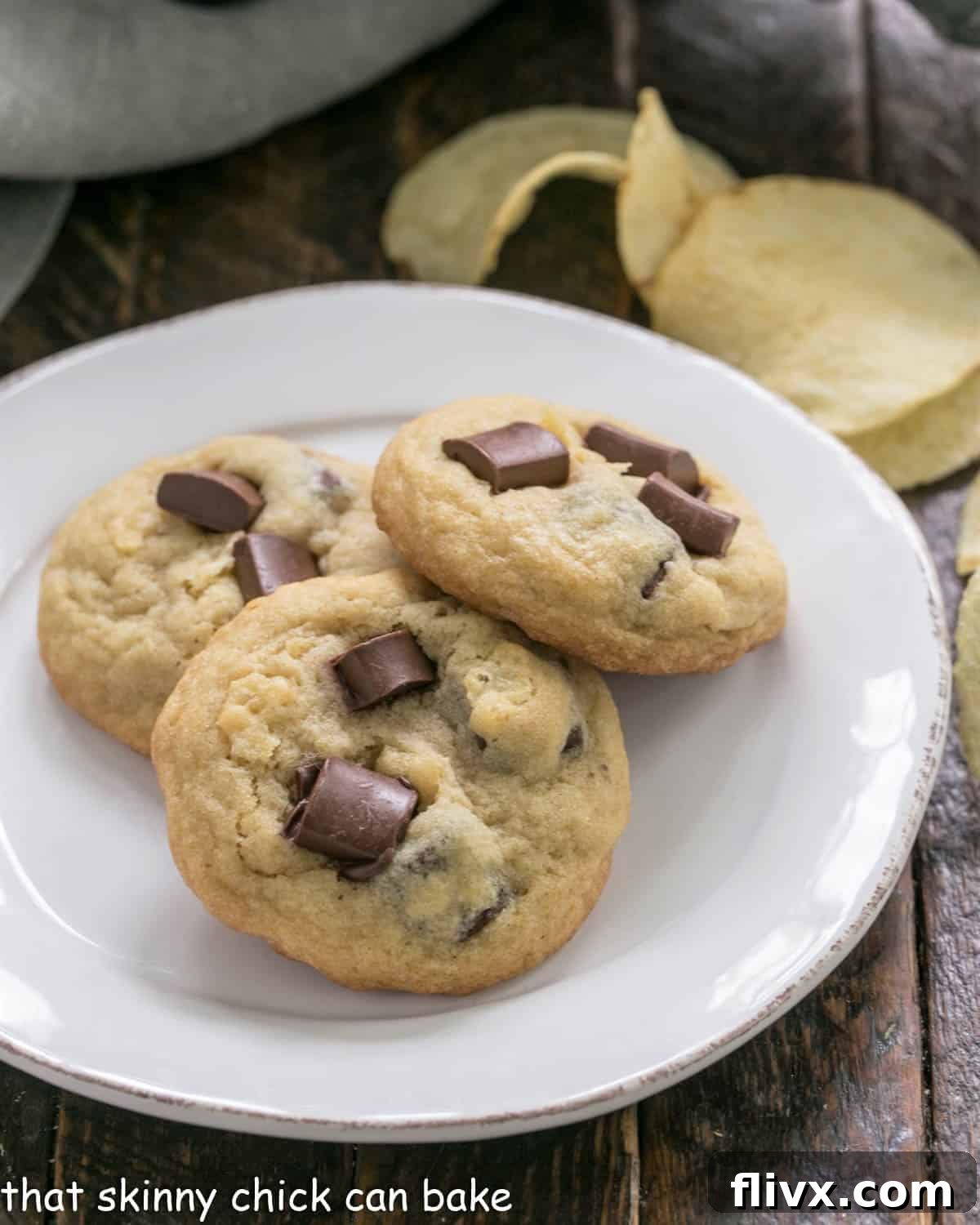 3 potato chip cookies on a white plate with chips in the background, highlighting the golden-brown exterior and delicious inclusions.