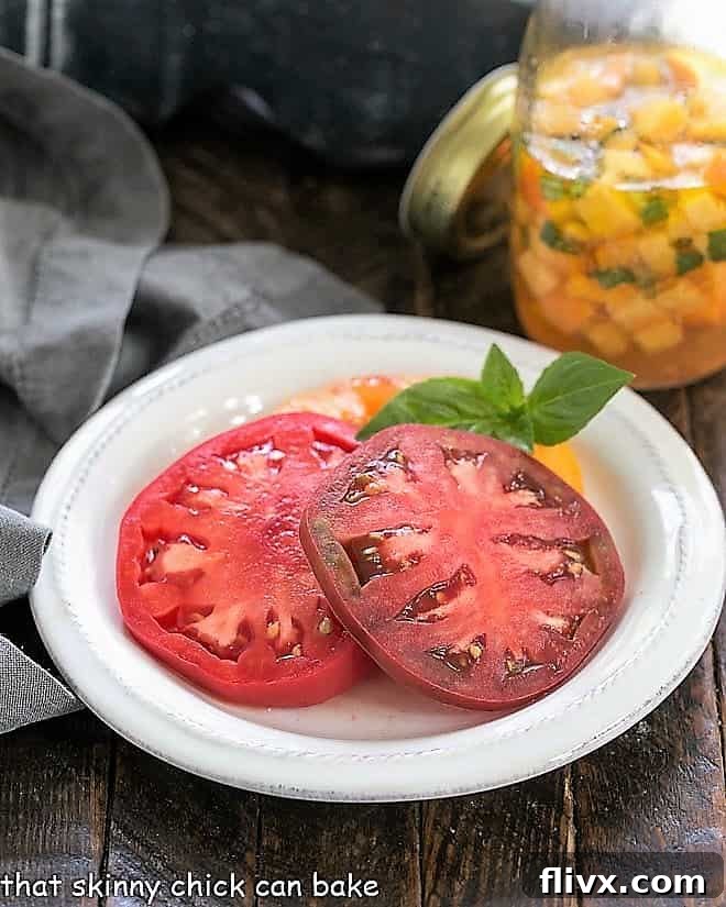 Tomatoes on a small white plate with a peach vinaigrette in the background.