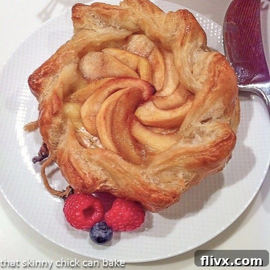 Baked Brie en croute with apples - an elegant appetizer that everyone will love! Apple Topped Baked Brie en Croute on a white serving plate, ready to be enjoyed.