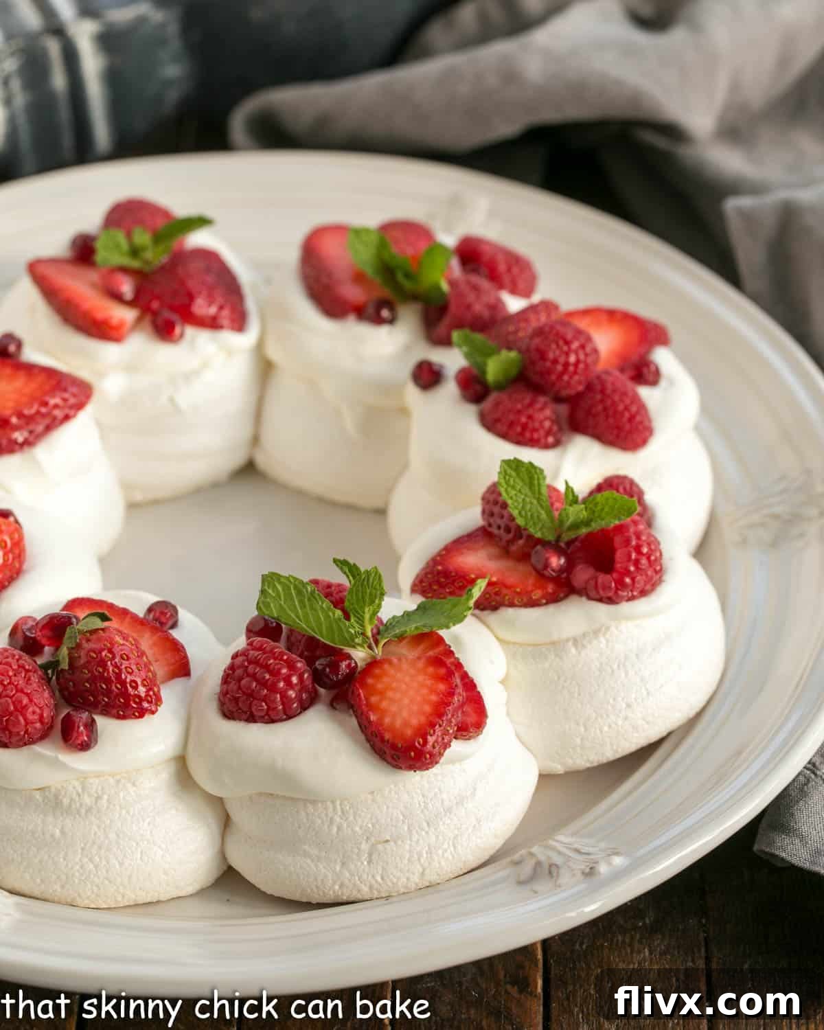 Christmas Cloud Wreath 2 Pavlova Wreath topped with berries and cream on a white serving plate.