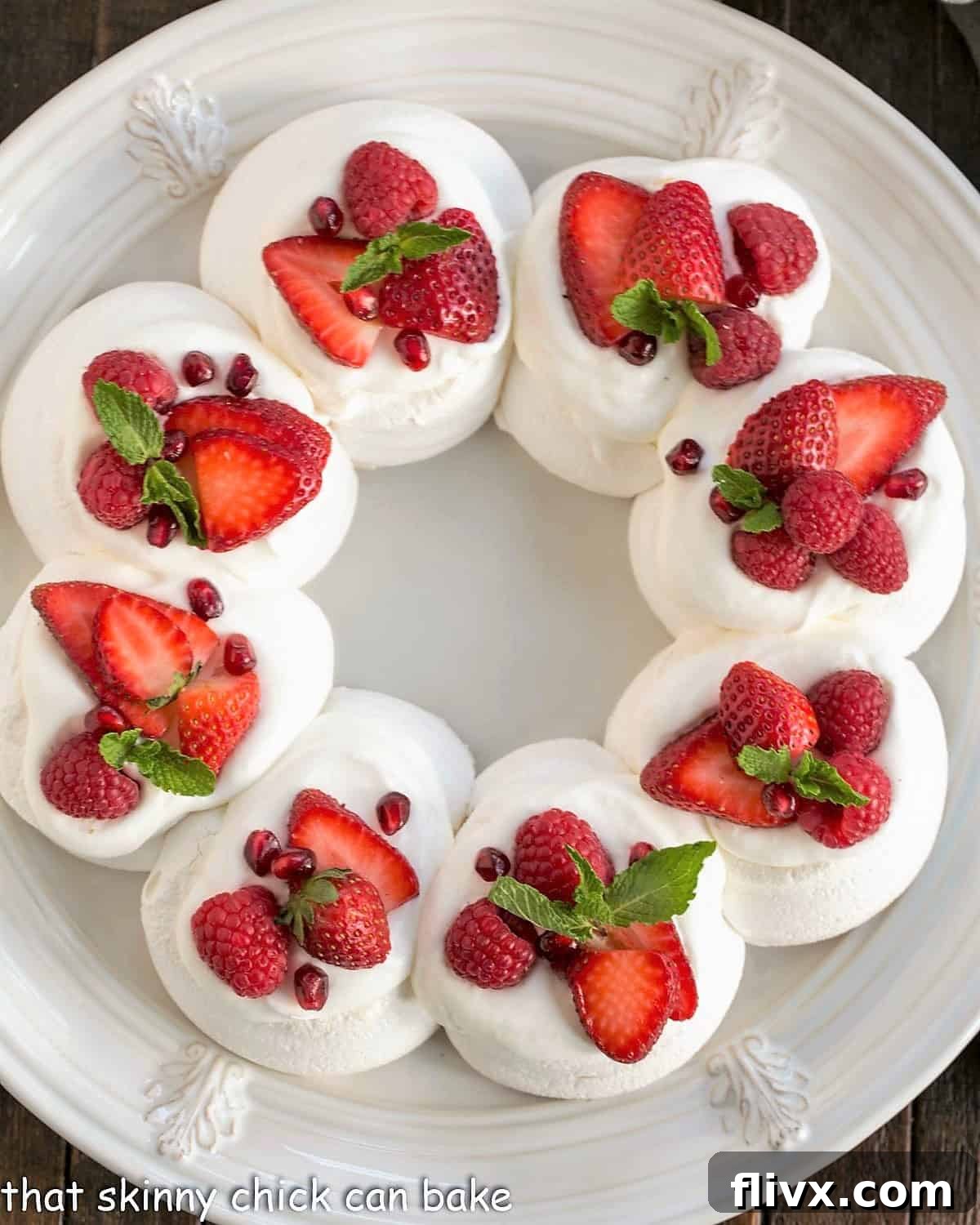Christmas Cloud Wreath 4 Overhead view of a Christmas Pavlova on a white plate topped with cream, berries and mint.
