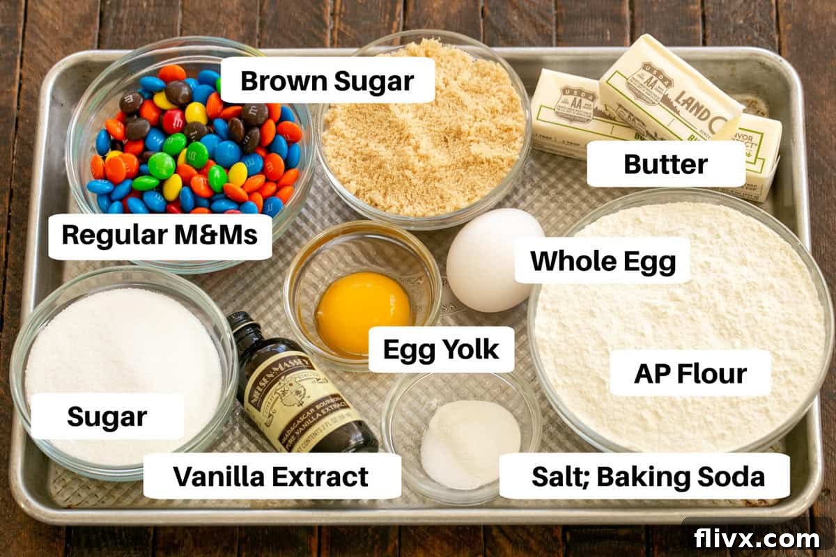 All the essential M&M Cookie Ingredients meticulously laid out on a sheet pan, clearly labeled for easy identification.
