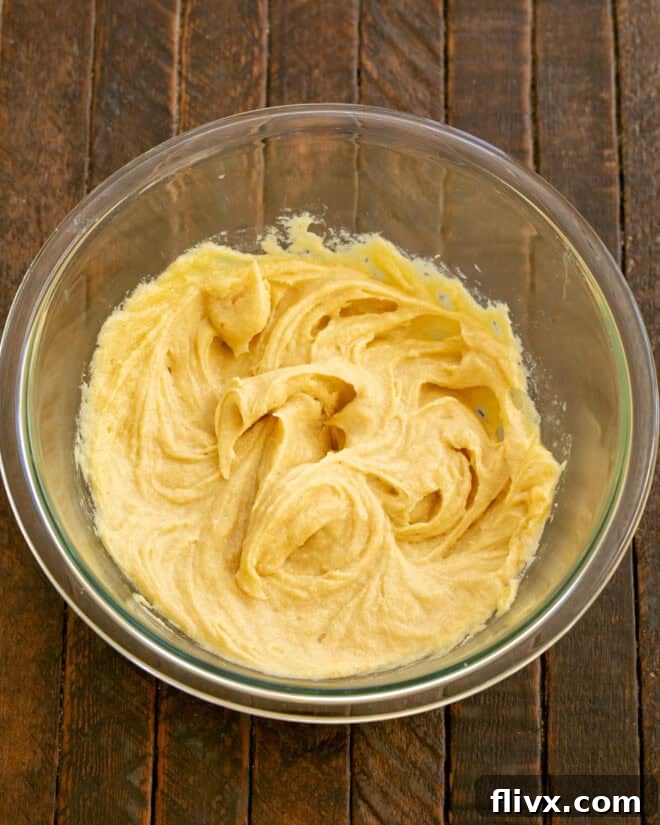 Step 2: Add the egg and additional egg yolk to the creamed butter and sugar mixture, mixing thoroughly until fully combined.