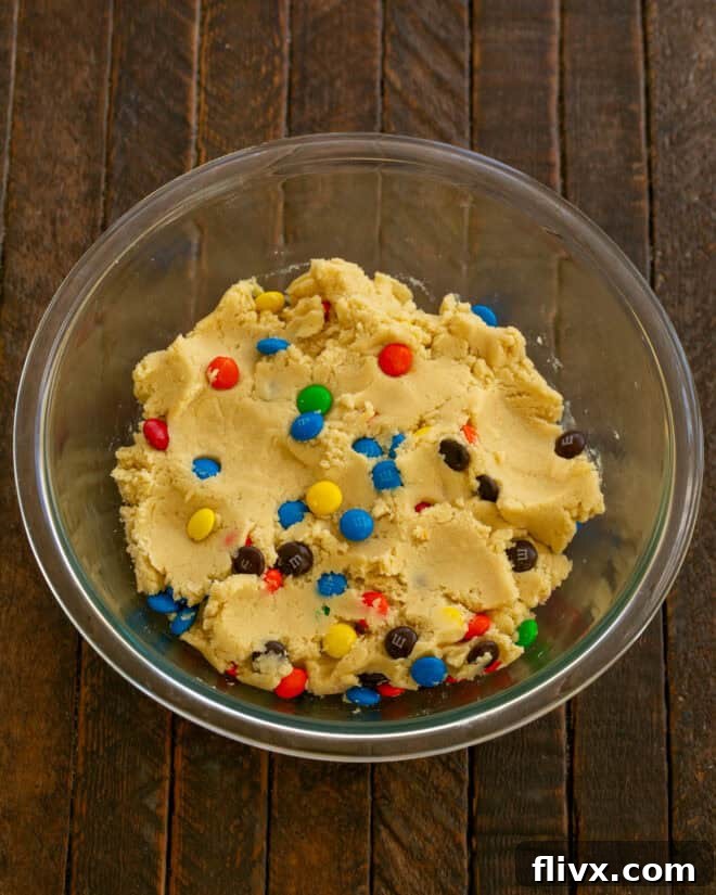 Step 4: Gently fold in the all-purpose flour until just combined, then add the M&M's, mixing minimally to avoid overworking the dough.