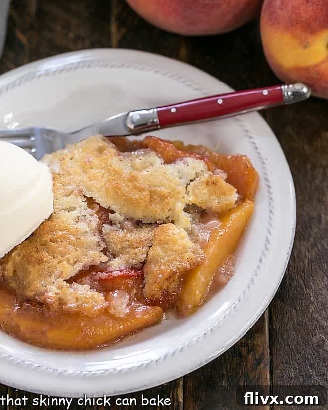 A slice of golden Easy Peach Cobbler served on a white dessert plate, generously topped with a melting scoop of creamy vanilla ice cream.
