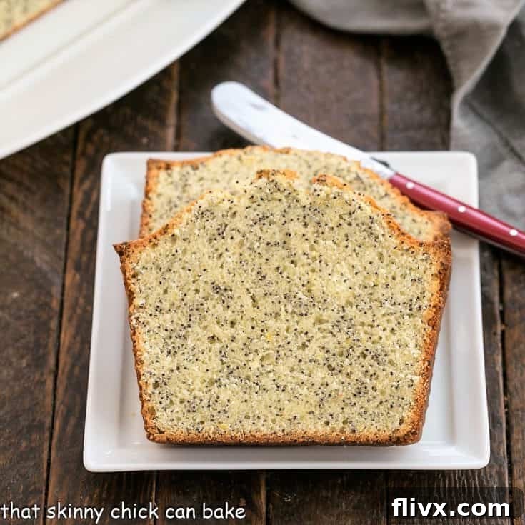 Two slices of lemon poppy seed bread on a square white plate with a red handle knife